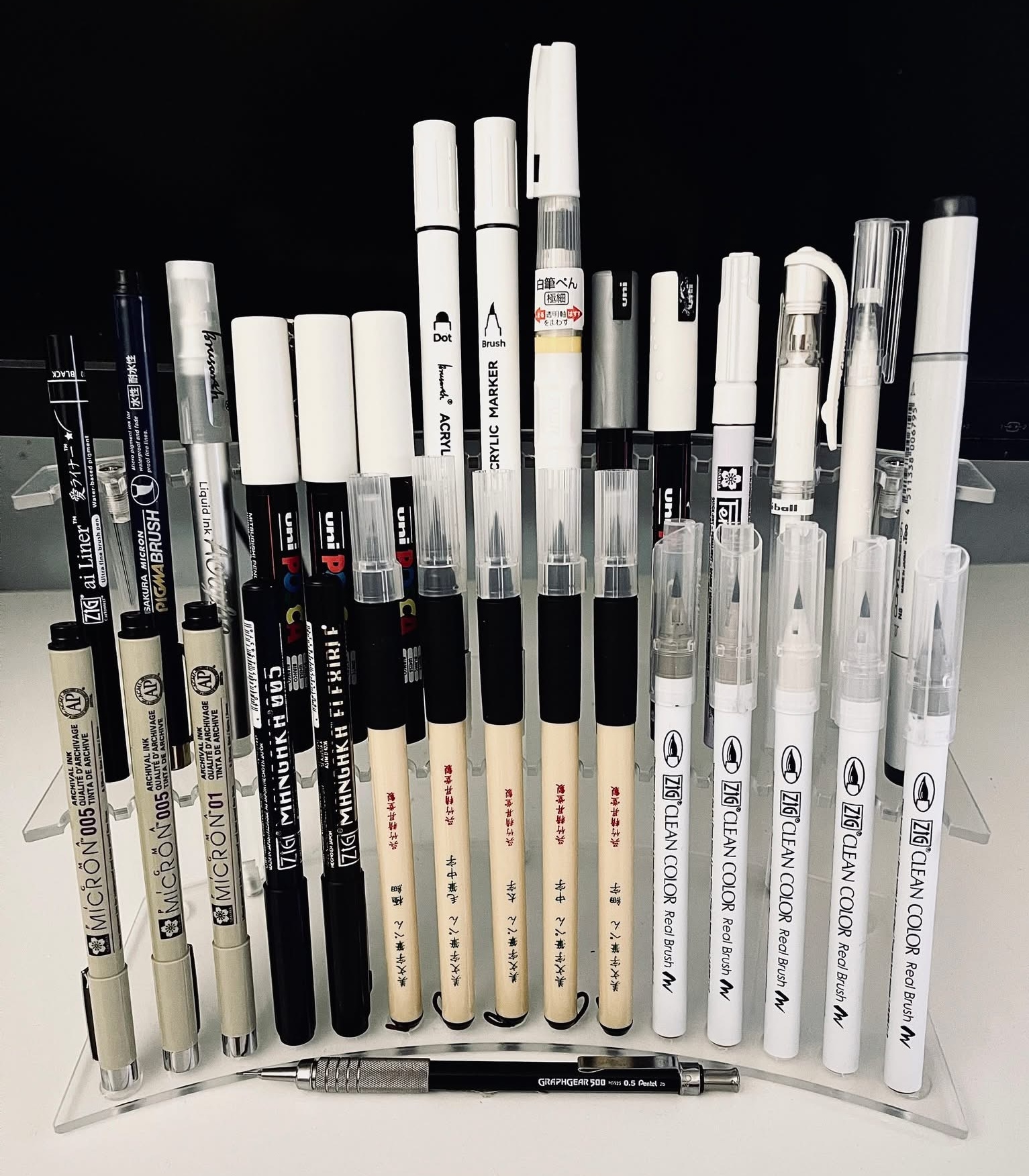 The Japanese ink pens and brush markers behind the hand-drawn artwork